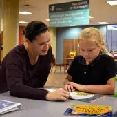 A teacher reads to a student