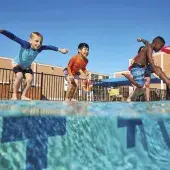 three children jumping into an outdoor pool