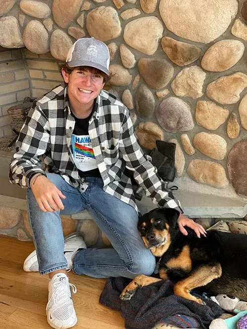 Jaxon Leasure sitting by a fireplace with his dog