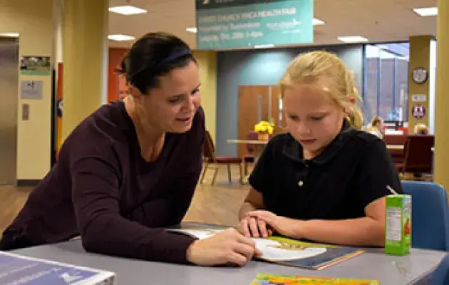 A teacher reads to a student