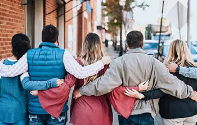 A group of friends locks arms outside a brick building