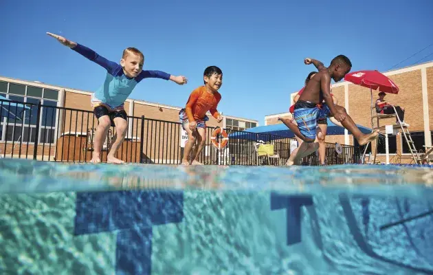 three children jumping into an outdoor pool