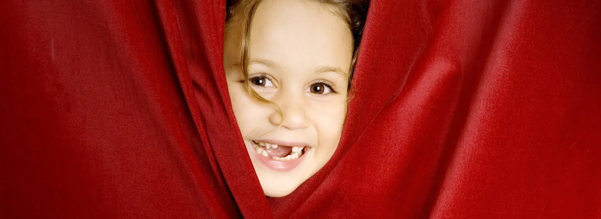 child peeking out from behind a curtain