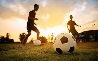 Youth playing soccer at sunset