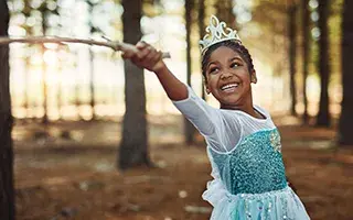 Girl dressed as princess holding wand in the woods