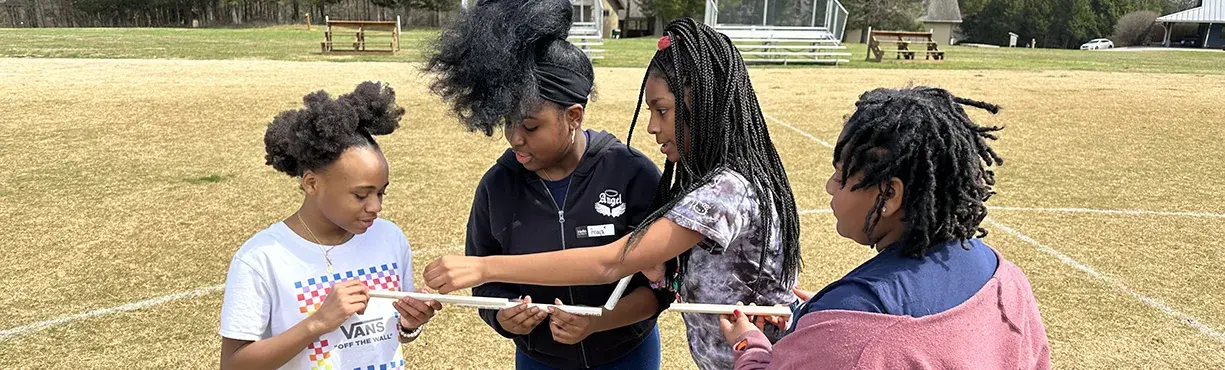 four young girls work together to solve a puzzling game
