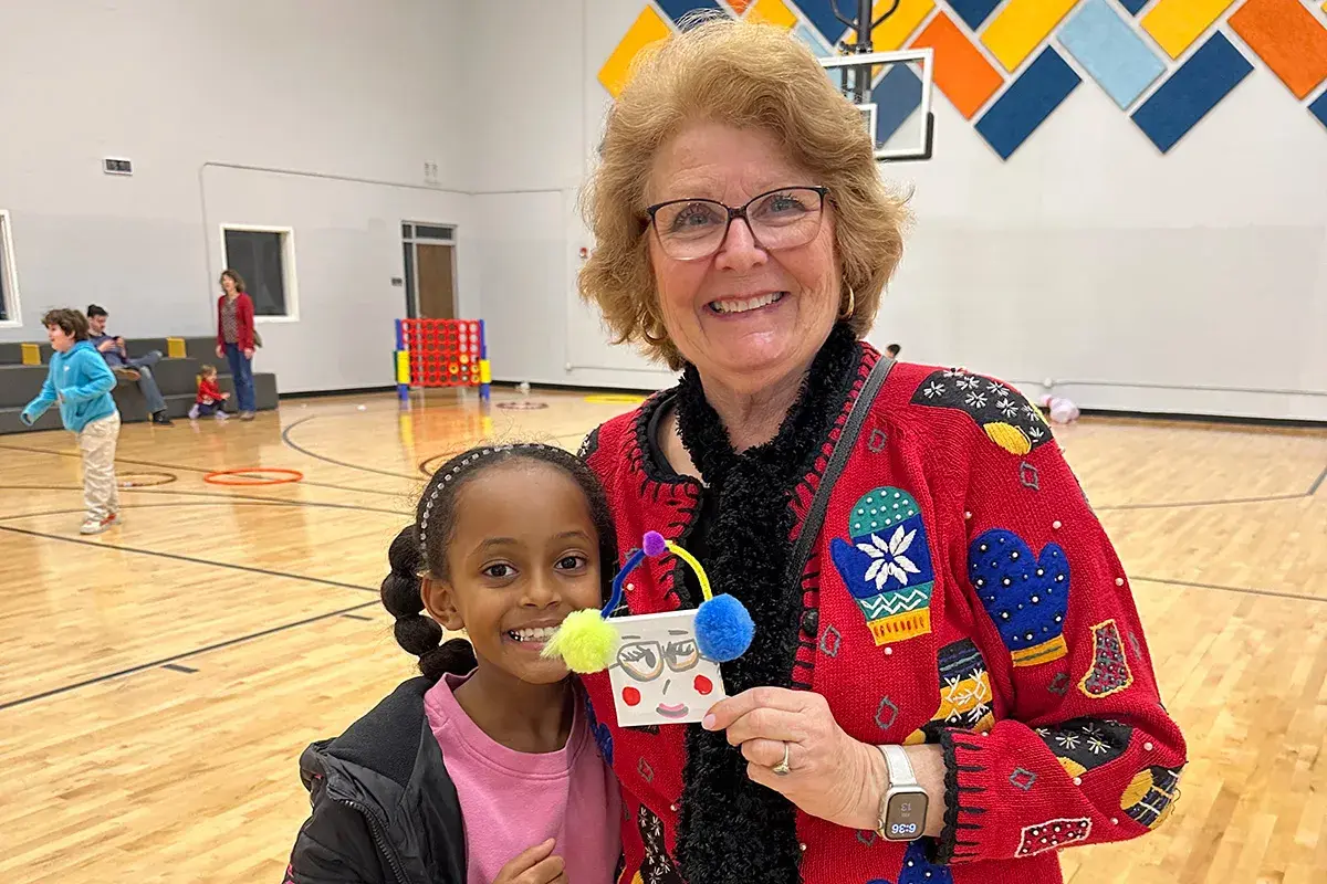 volunteer smiling with one student in a gymnasium