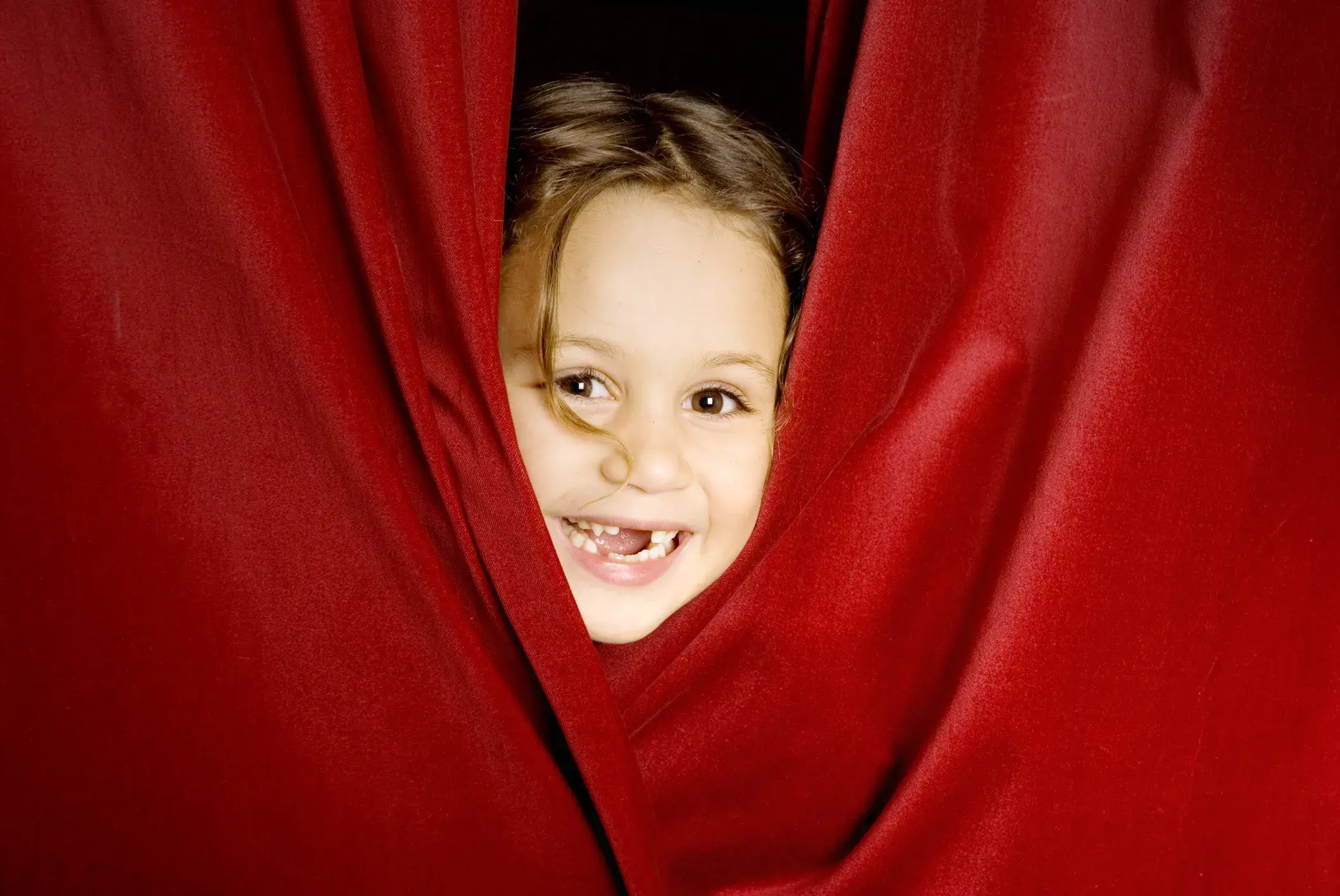 child peeking out from behind a curtain