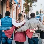 A group of friends locks arms outside a brick building